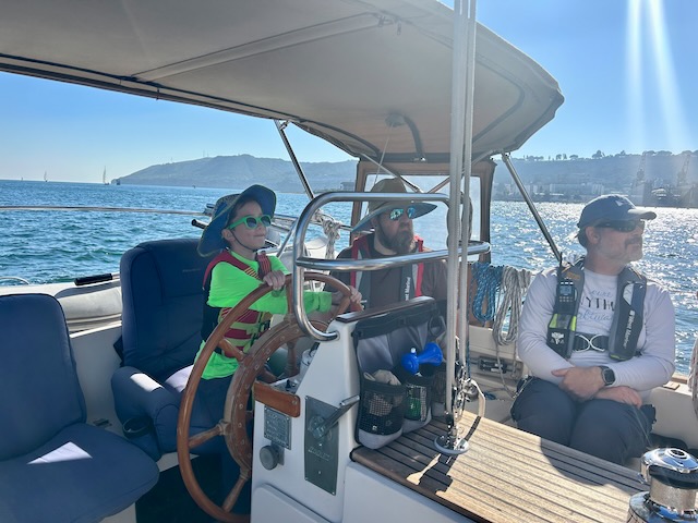 A young boy at the helm of the boat as I look ahead, unconcerned about what the boy is doing.